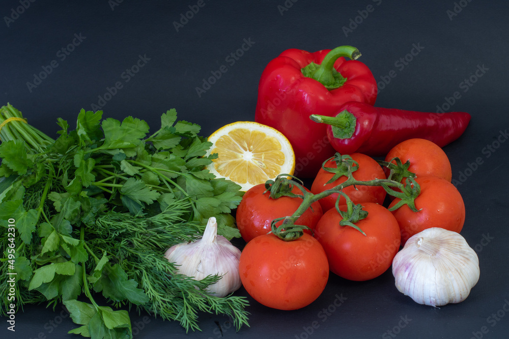 Red vegetables on a black background. Peppers and tomatoes, garlic Red vegetables on a black background. Peppers and tomatoes, garlic