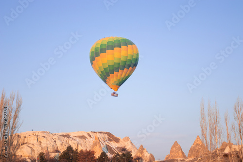 A bright green hot air balloon flying over the mountains landscape