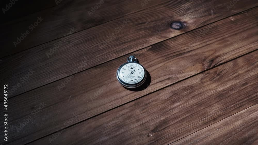 Vintage stopwatch lies on wooden table and counts the seconds