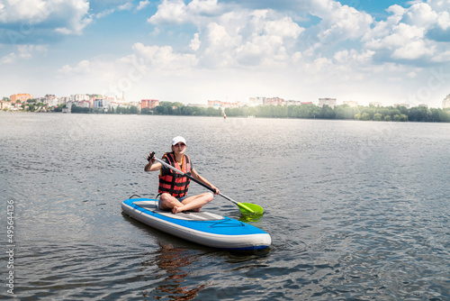 Charming smiling woman rides a sup paddle board around city lake