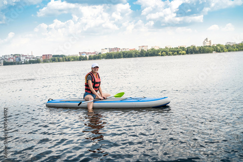 young slim woman is riding a SUP board on the city lake