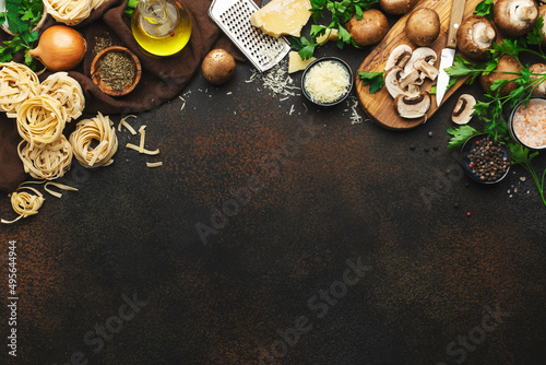 Fototapeta Naklejka Na Ścianę i Meble -  Italian uncooked pasta, brown champignons mushrooms, vegetables, cheese and ingredients for tasty cooking on old kitchen table background, dark style, top view. Food banner