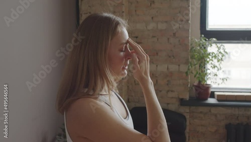 Chest-up of young Biracial female yoga instructor standing with eyes closed in studio at daytime, showing pranayama breathing technique and talking