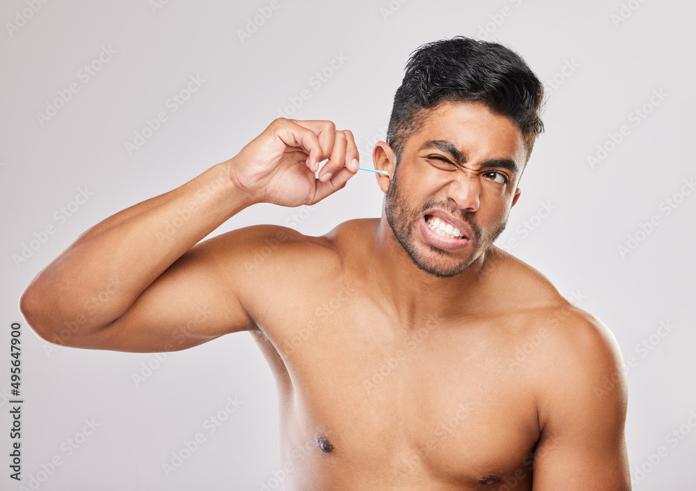 I dont like this feeling. Shot of a young man cleaning his ears against a grey background. I dont like this feeling. Shot of a young man cleaning his ears against a grey background.