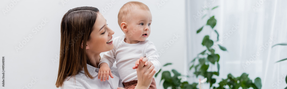 Positive family doctor holding hand of infant boy in clinic, banner. Positive family doctor holding hand of infant boy in clinic, banner.