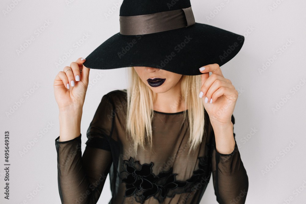 Close up portrait of stylish elegant woman covering face by hat and holding hat. Stylish woman in holiday blouse over isolated background Close up portrait of stylish elegant woman covering face by hat and holding hat. Stylish woman in holiday blouse over isolated background