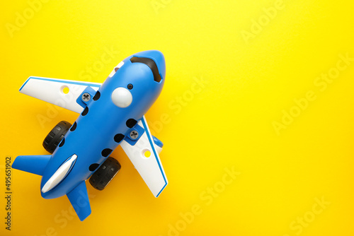 Plastic toy plane on yellow background with space for text