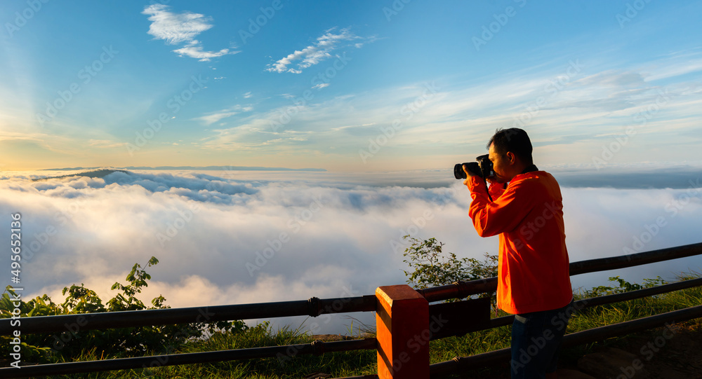 Panorama photographer standing on top of Mountain at sunset with Mist.Asian male backpack in nature during sunset Relax time on holiday concept travel at Pha mor i dang,Sisaket province,Thailand,ASIA. - obrazy, fototapety, plakaty 