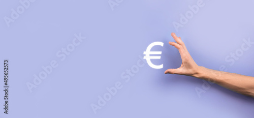 Businessman holds money coin icons EUR or Euro on dark tone background..Growing money concept for business investment and finance © Ivan