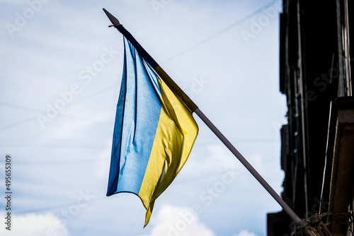National flag of Ukraine on the pole on the house wall. Defocused