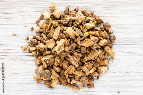 Photos top view of pile of chopped dried burdock roots on gray wooden board close up