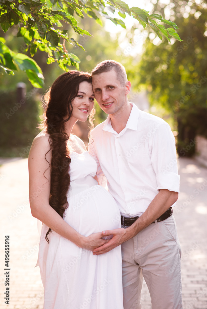 Obraz premium Happy and young pregnant couple in park in summer