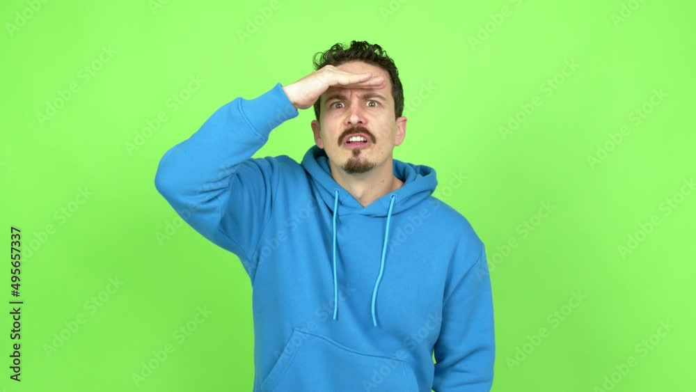 Man looking far away with hand to look something over isolated background. Green screen chroma key Man looking far away with hand to look something over isolated background. Green screen chroma key
