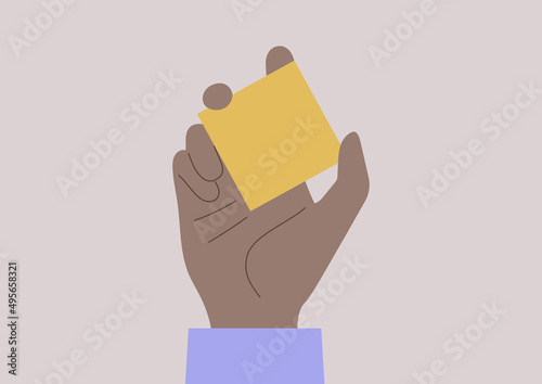 A hand holding a yellow square note sheet, copy space