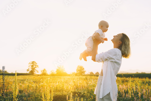 Loving mother and baby at sunset. Beautiful woman and small child in nature background. Concept of natural motherhood. Happy healthy family at summer outdoors. Positive human emotions and feelings.