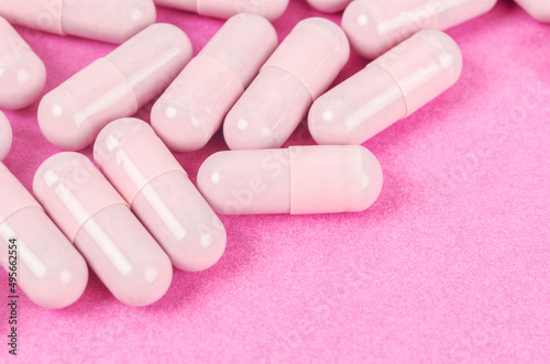 Pink capsule pills on pink background