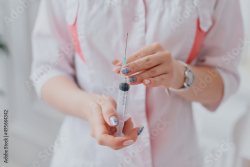 a doctor in a white coat demonstrates a syringe with a needle in his hands