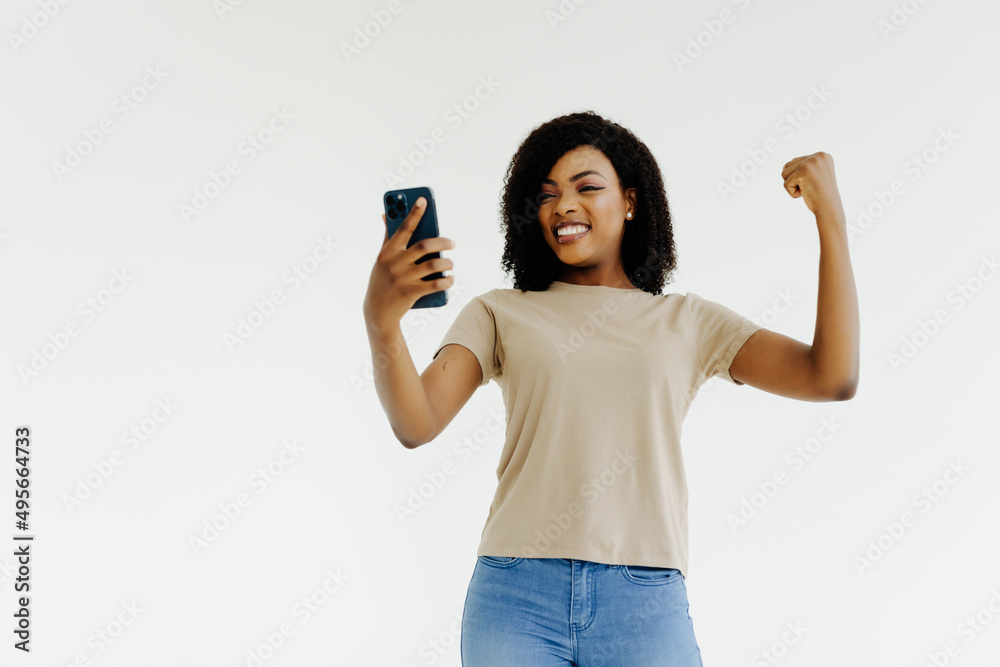 African woman with striped shirt celebrating a victory with a mobile African woman with striped shirt celebrating a victory with a mobile