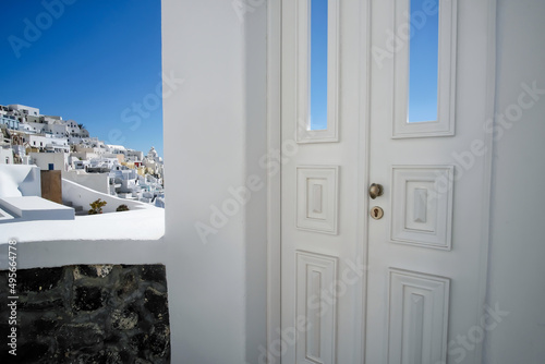 Typical design white decoration door next to an alley with a breathtaking view of the village Fira and the aegean sea in Santorini © DIMITRIOS