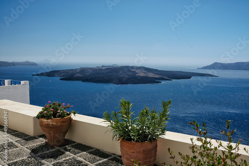 Panoramic view of the volcano Nea Kameni from a rooftop decorated with flower pots in Santorini