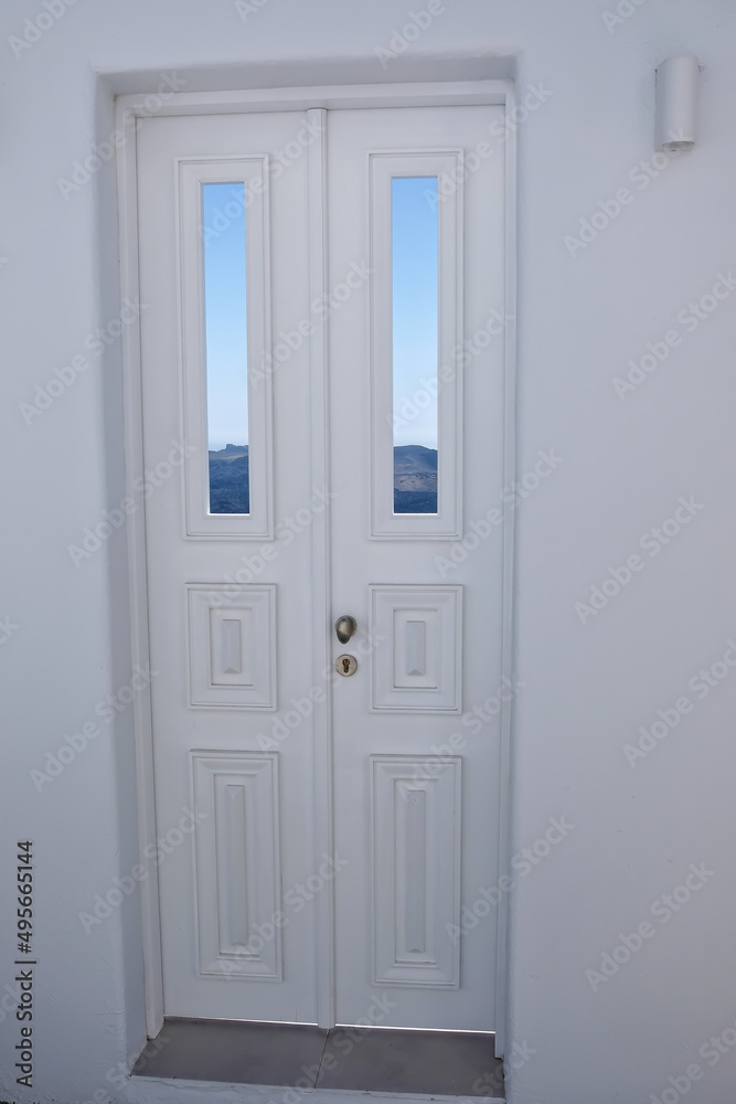 A typical white traditional door, the blue sky , the aegean sea and the volcano of Santorini in the background A typical white traditional door, the blue sky , the aegean sea and the volcano of Santorini in the background