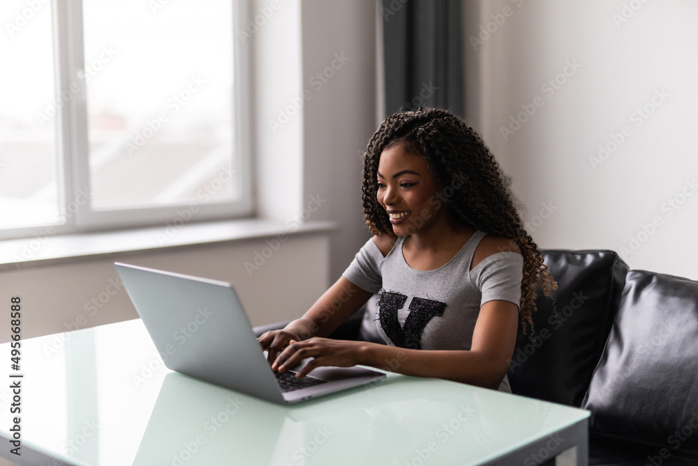 Successful african american young woman using and typing on laptop in modern office. Successful african american young woman using and typing on laptop in modern office.