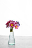 Bouquet of first spring flowers in blue vase on white background.