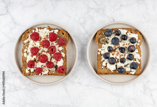 Whole grain bread toasts with cottage cheese and fresh raspberries ,blueberries and with flax seeds, on a white background .Top view .Dieting concept .