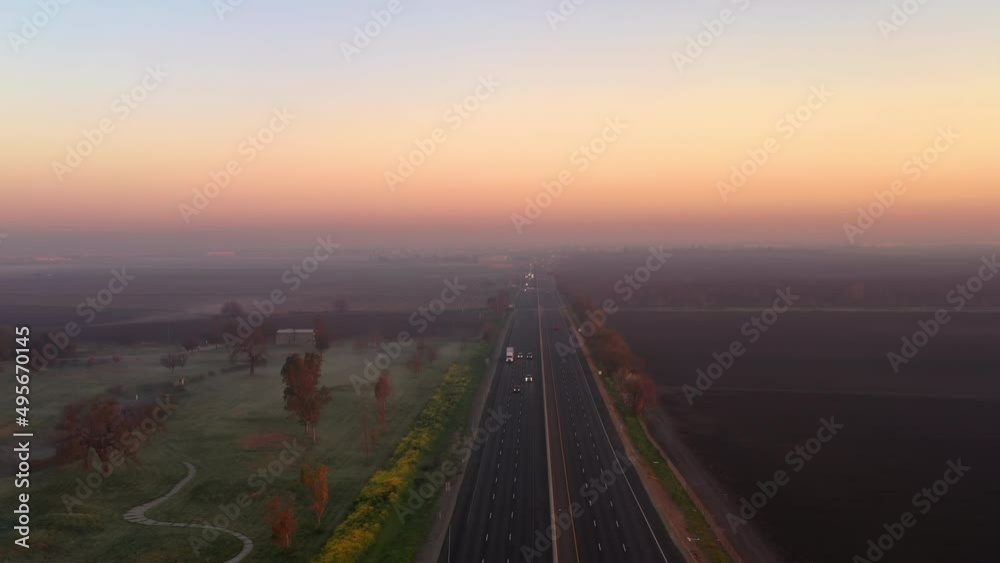 Cars and trucks on Highway 99 in the morning. Big rig trucks and cars drive along the scenic highway running across the Central Valley in California landscape at sunrise Cars and trucks on Highway 99 in the morning. Big rig trucks and cars drive along the scenic highway running across the Central Valley in California landscape at sunrise