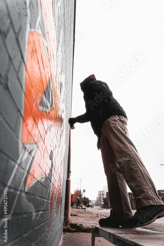 Side view of the artist drawing colorful graffiti on the wall of the building photo