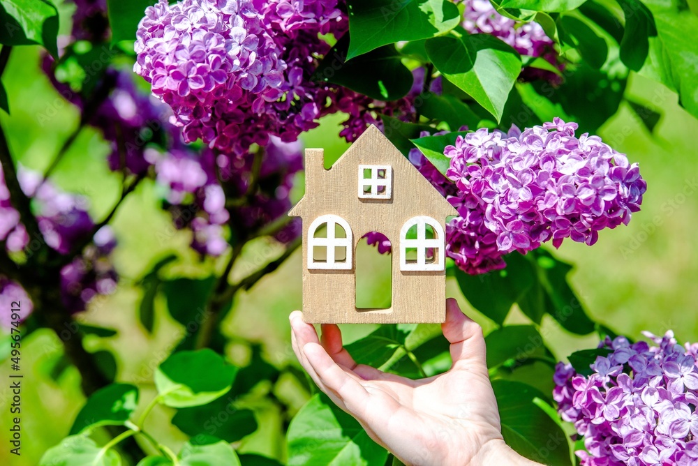 The girl holds in her hand the symbol of the house against the background of blooming lilac
The girl holds in her hand the symbol of the house against the background of blooming lilac