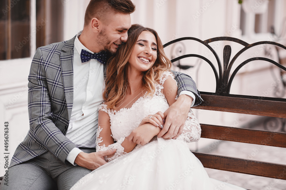 wedding day. beautiful bride in white long dress and young groom wearing in black suit are hugging in historic europe town wedding day. beautiful bride in white long dress and young groom wearing in black suit are hugging in historic europe town