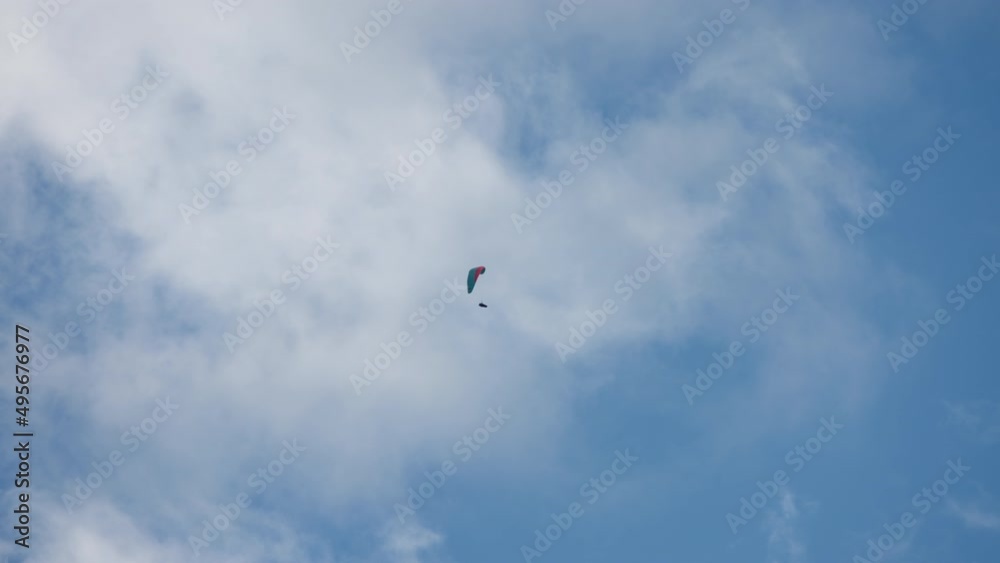 Parachutist flying between clouds and blue sky. Slow motion. Extreme sports activities concept. Parachutist flying between clouds and blue sky. Slow motion. Extreme sports activities concept.