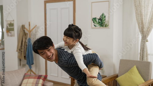 Foto Happy Asian daughter sitting playing on her father’s back at home