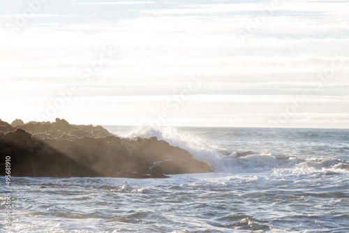 waves hitting rocks on the shore and beach