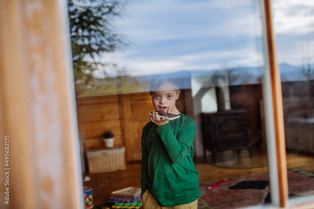 Sad little boy with Down syndrome using smartphone at home Sad little boy with Down syndrome using smartphone at home