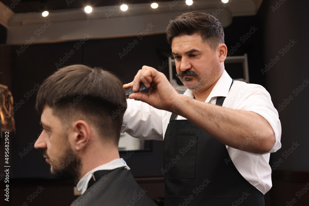 Fototapeta premium Professional hairdresser making stylish haircut in barbershop