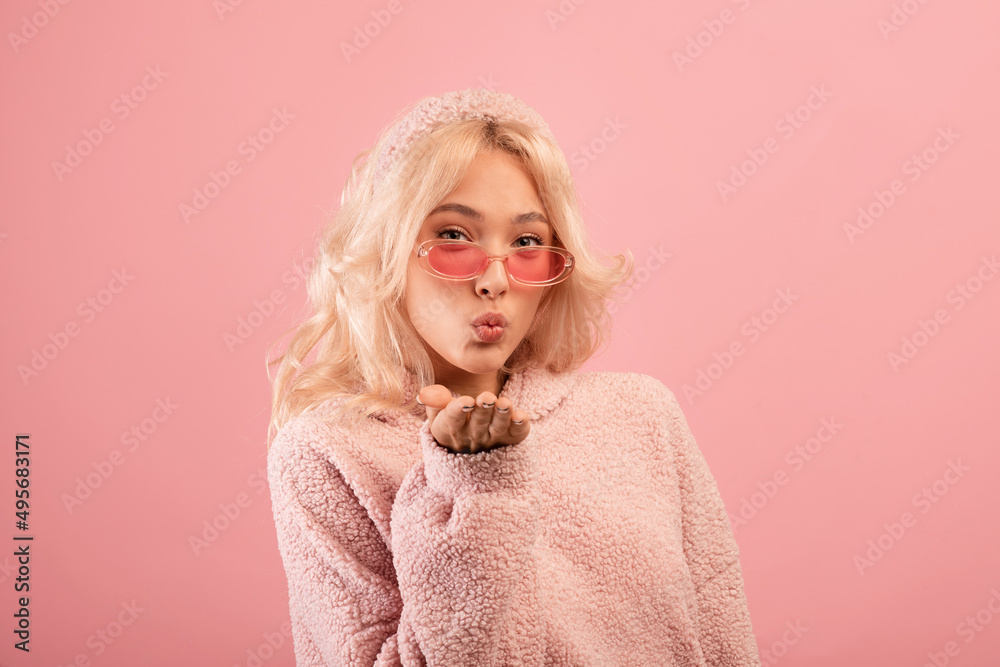 Pretty stylish lady blowing air kiss at camera, playful woman being flirty, sending her love, pink studio background Pretty stylish lady blowing air kiss at camera, playful woman being flirty, sending her love, pink studio background