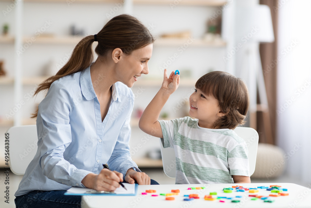Cute little boy showing and pronouncing sound O with his teacher, exercising together at classroom, free space Cute little boy showing and pronouncing sound O with his teacher, exercising together at classroom, free space