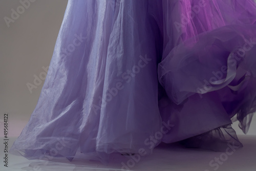 Сlose-up of a blue chiffon dress curiously bending on girl in the studio. Lavender fabric tulle texture