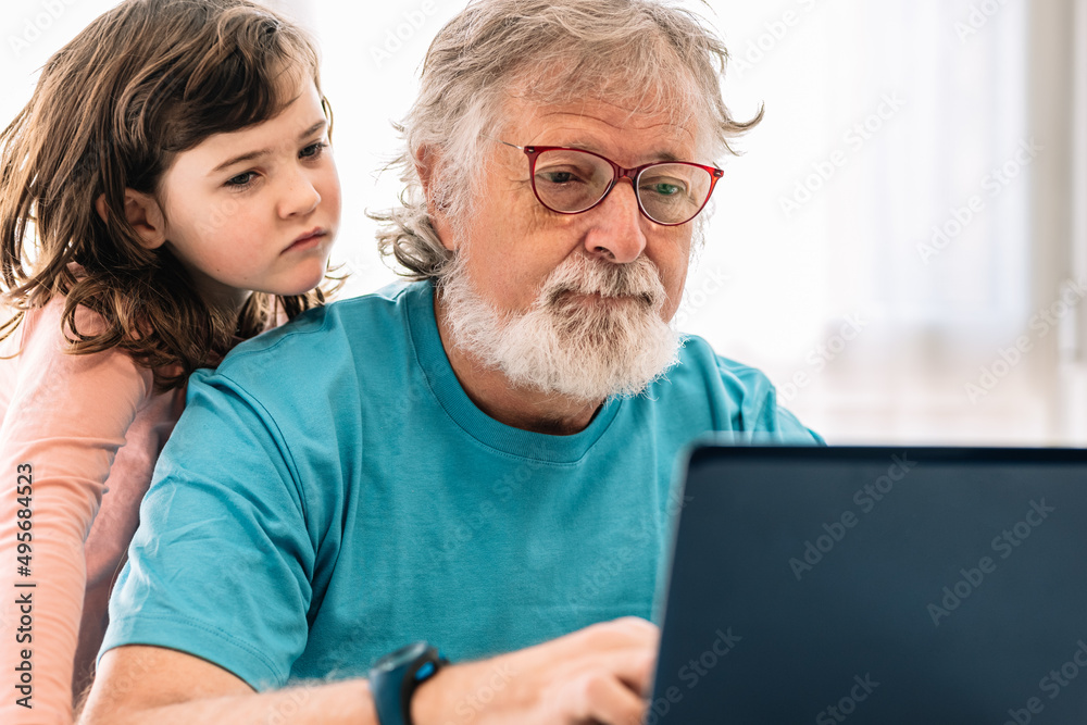 Grandfather browsing laptop with girl