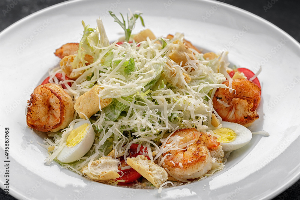 Caesar salad with shrimps, on a dark background. Caesar salad with shrimps, on a dark background.