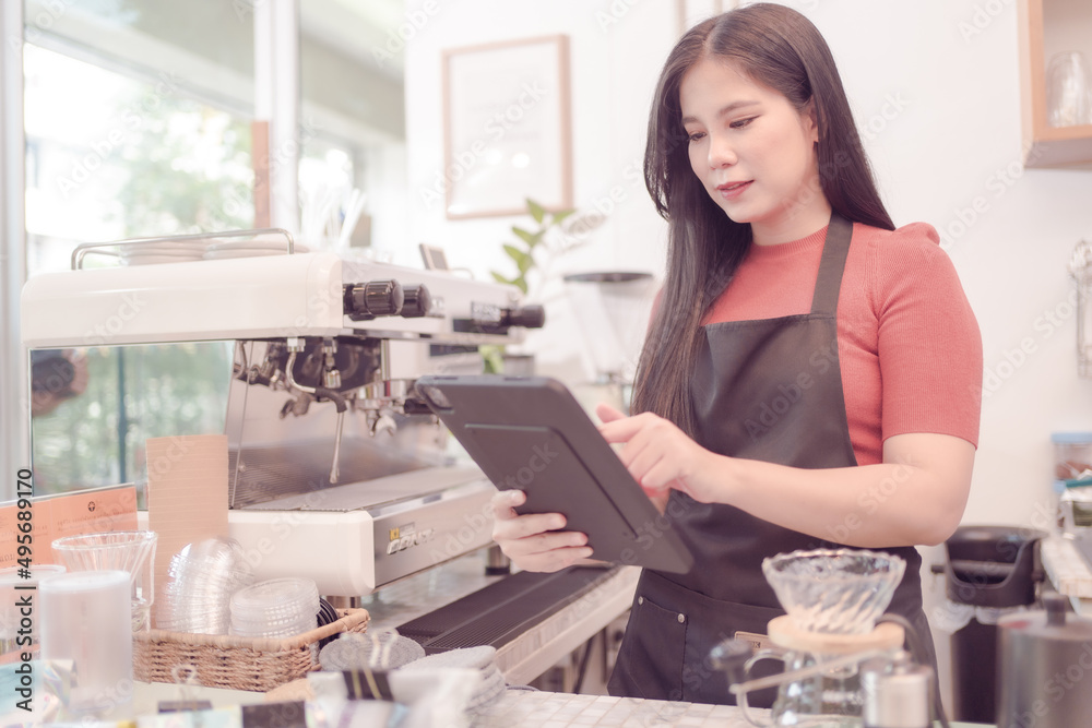 Asian woman who owns this coffee shop. checking Daily coffee shop sales data on his tablet and it seems Sales will be especially good. which made the owner very happy Asian woman who owns this coffee shop. checking Daily coffee shop sales data on his tablet and it seems Sales will be especially good. which made the owner very happy