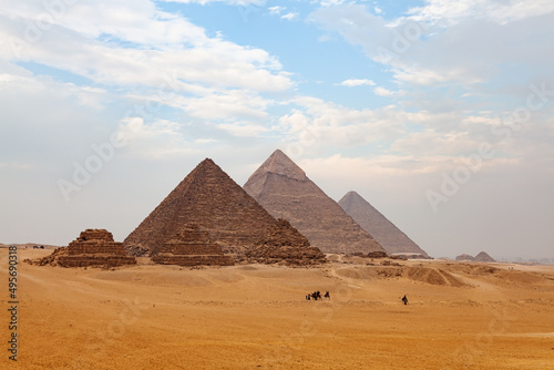 View of The Giza Plateau with tourists and native people riding camel and The Great Pyramid in the background.