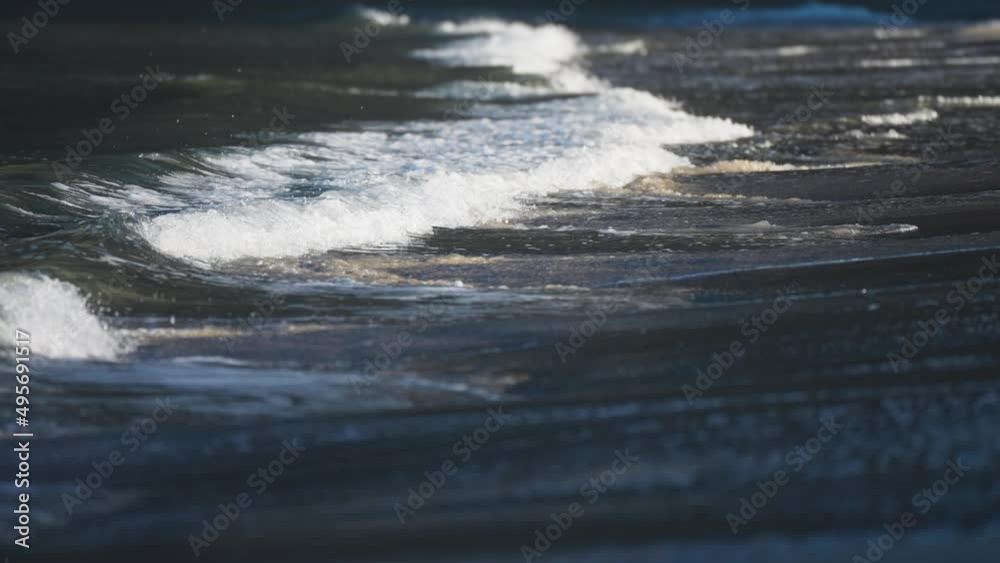 Waves roll slowly on the shallows of the sandy beach in Ersfjord. White foam rising and disappearing swallowed by sand. Slow-motion, pan follow. Waves roll slowly on the shallows of the sandy beach in Ersfjord. White foam rising and disappearing swallowed by sand. Slow-motion, pan follow.