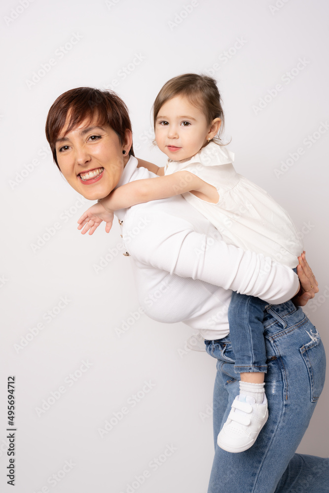 Photo of pretty young mommy hugging little daughter standing isolated over white background. Motherhood concept. Photo of pretty young mommy hugging little daughter standing isolated over white background. Motherhood concept.