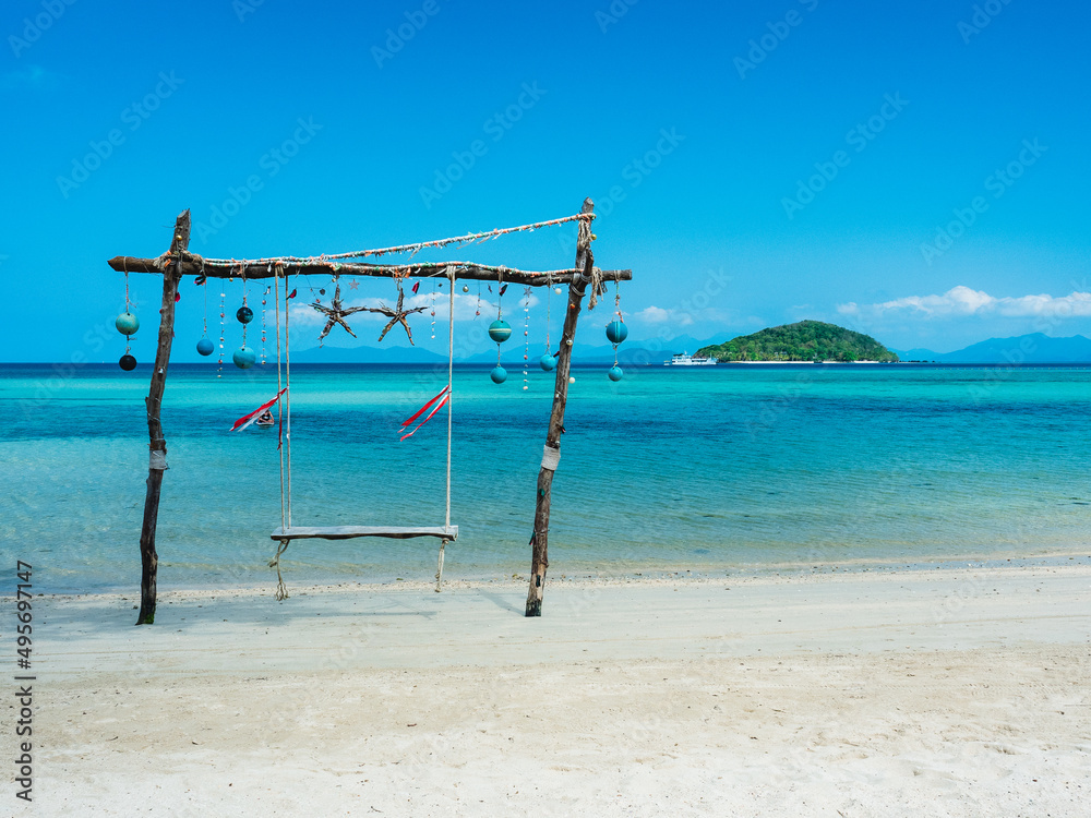 Scenic white sand beach tropical island with relax wooden swing and crystal clear turquoise sea water against blue sky in summer. Koh Mak Island, Trat, Thailand. Scenic white sand beach tropical island with relax wooden swing and crystal clear turquoise sea water against blue sky in summer. Koh Mak Island, Trat, Thailand.