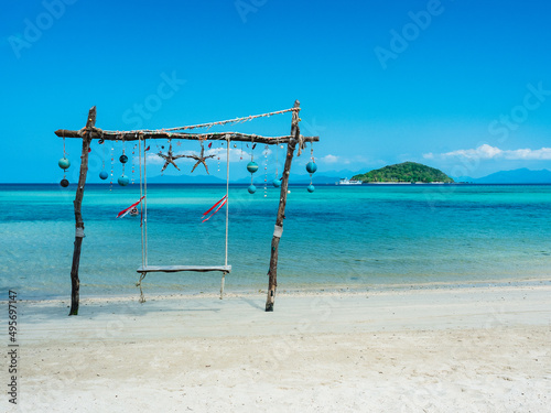 Scenic white sand beach tropical island with relax wooden swing and crystal clear turquoise sea water against blue sky in summer. Koh Mak Island, Trat, Thailand.