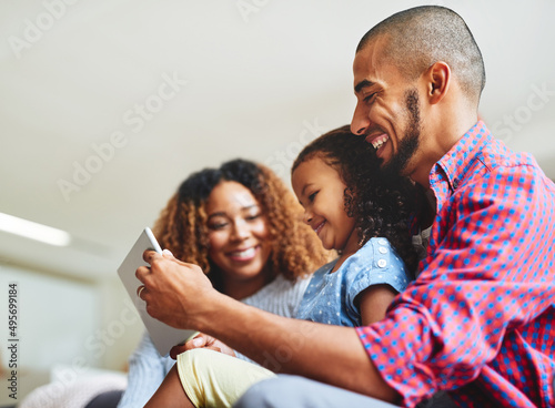 Family time and screen time combined. Shot of an adorable little girl and her parents using a digital tablet together on the sofa at home. © Delmaine D/peopleimages.com