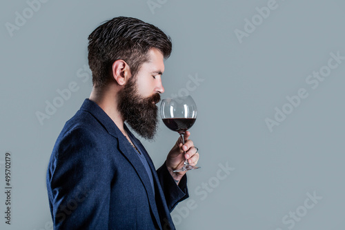 Man with a glass of red wine in his hands. Beard man, bearded, sommelier tasting red wine. Sommelier, degustator with glass of wine, winery, male winemaker photo